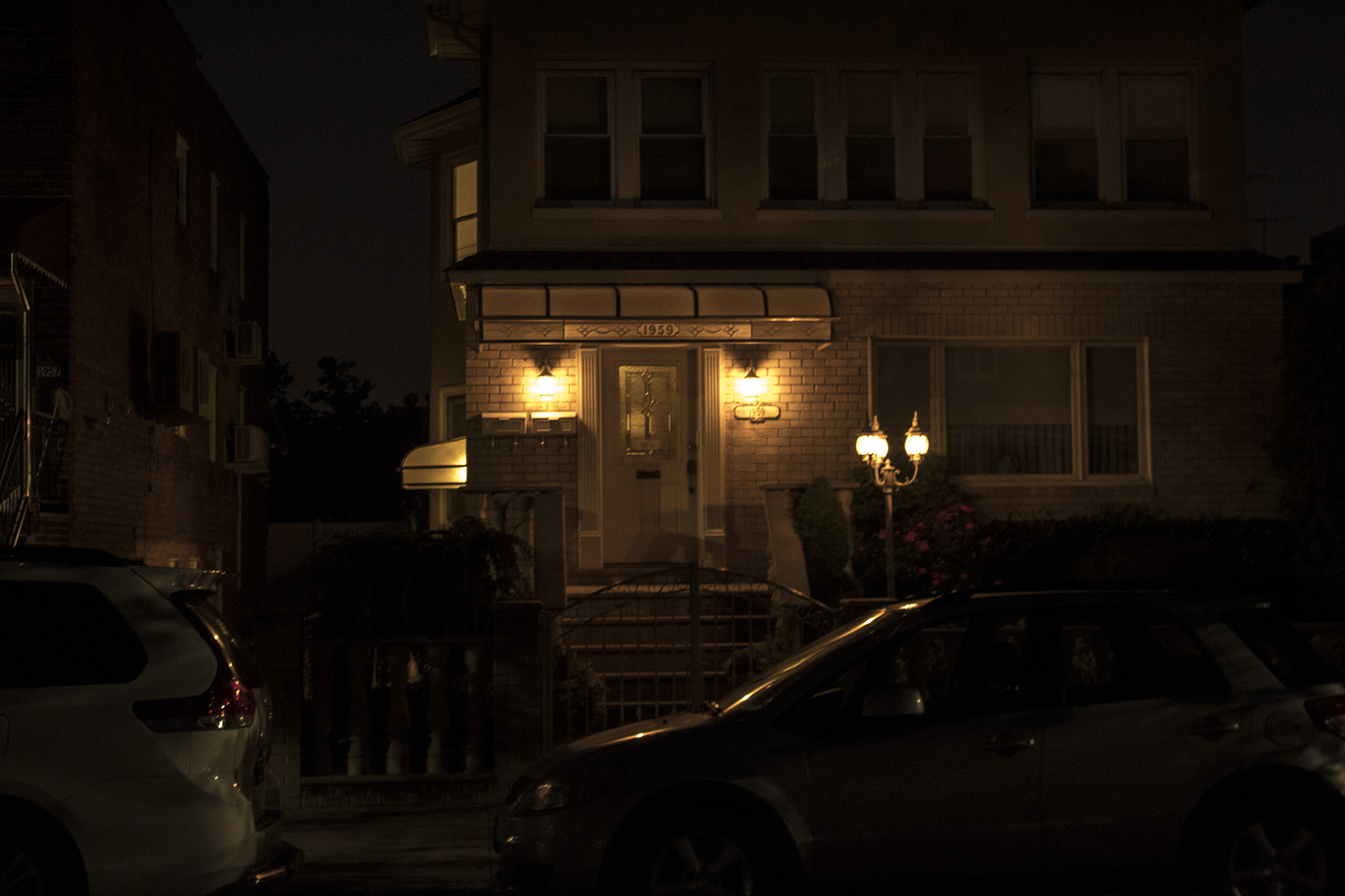 house and cars illuminated by streetlamp