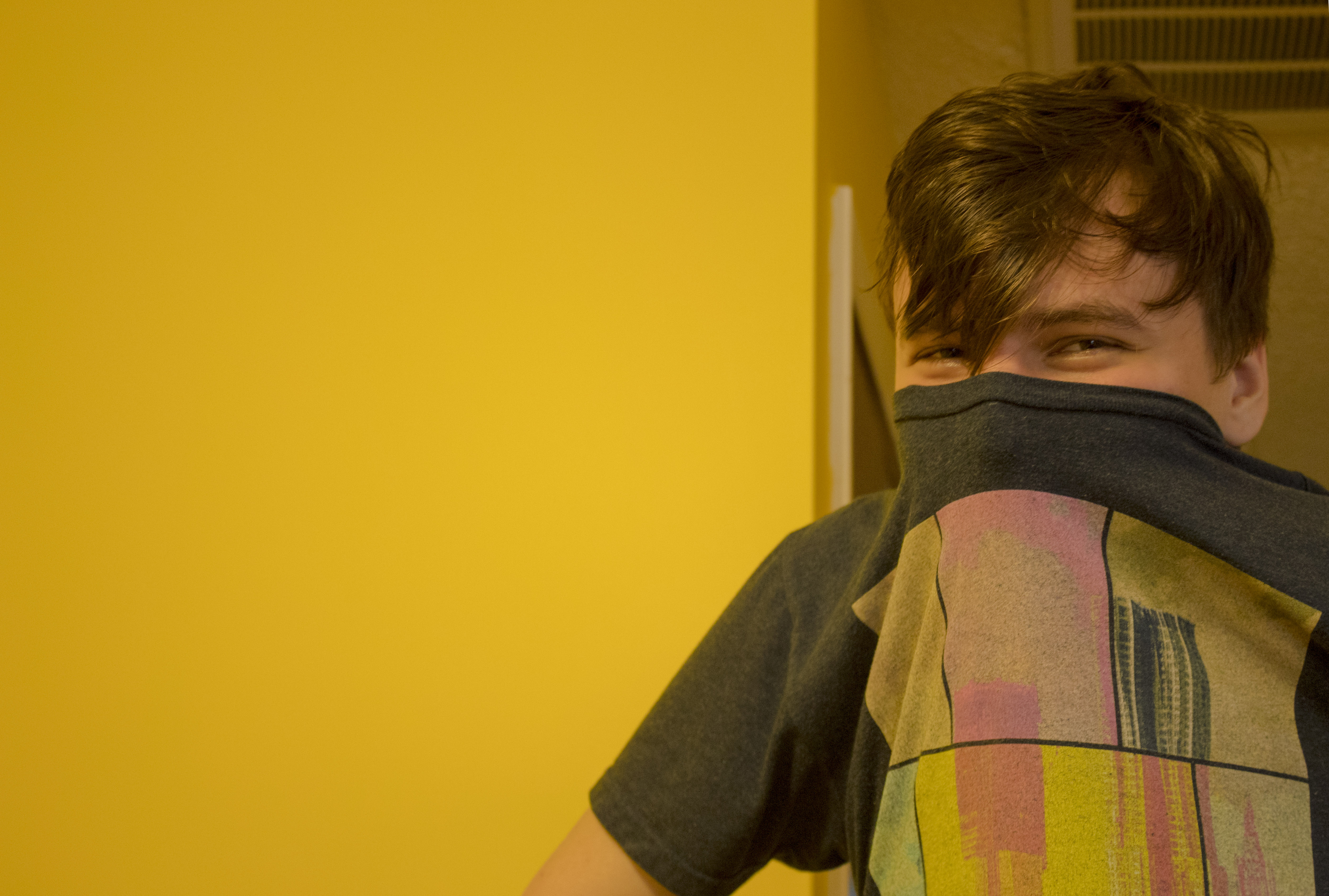 man smiling into camera with shirt over his mouth