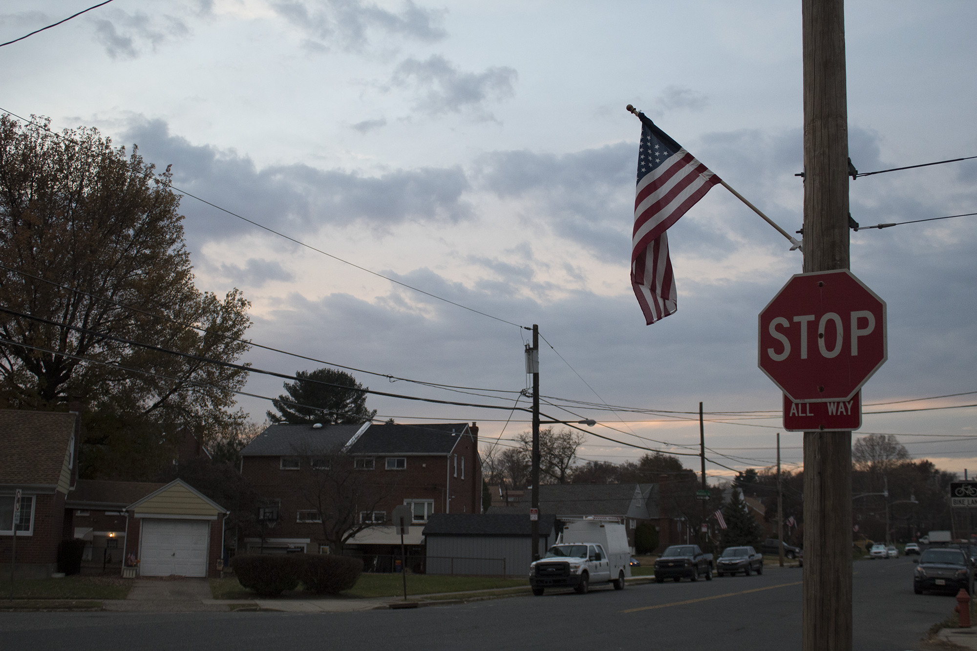 stop sign in suburban neighborhood with american flag hanging from it